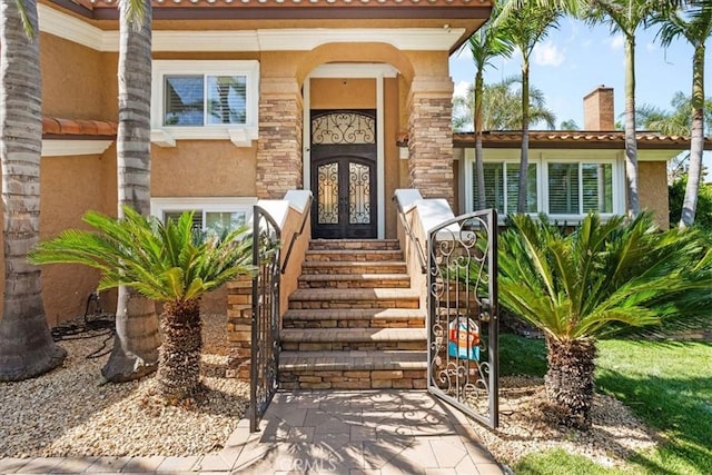 10920 Beechwood Dr, Rancho Cucamonga, CA 91737 - view of exterior entry with french doors, stucco siding, a chimney, and a gate