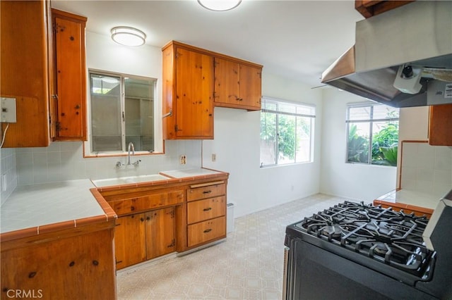 18126 S Denker Ave, Gardena, CA 90248 - kitchen featuring wall chimney range hood, black range with gas cooktop, tile counters, and brown cabinets