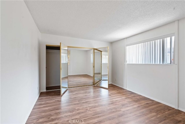 5500 Lindley Ave Unit 206, Encino, CA 91316 - unfurnished bedroom with multiple windows, a textured ceiling, wood finished floors, and a closet