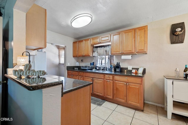 272 E 69th St, Long Beach, CA 90805 - kitchen featuring light tile patterned floors, a peninsula, and dark stone counters