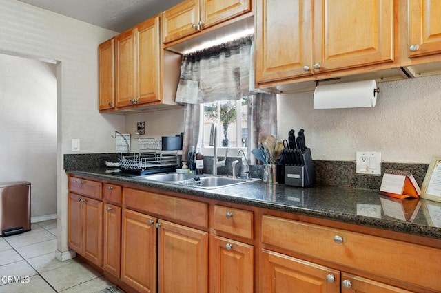 272 E 69th St, Long Beach, CA 90805 - kitchen with light tile patterned flooring, brown cabinetry, and dark stone counters