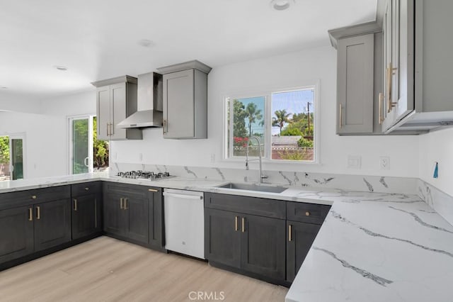 7812 Fairchild Ave, Winnetka, CA 91306 - kitchen with wall chimney range hood, stainless steel appliances, light stone counters, light wood-type flooring, and a peninsula