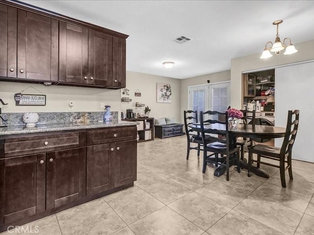 10316 S San Pedro St, Los Angeles, CA 90003 - kitchen featuring dark brown cabinetry, a chandelier, light tile patterned floors, and light stone counters