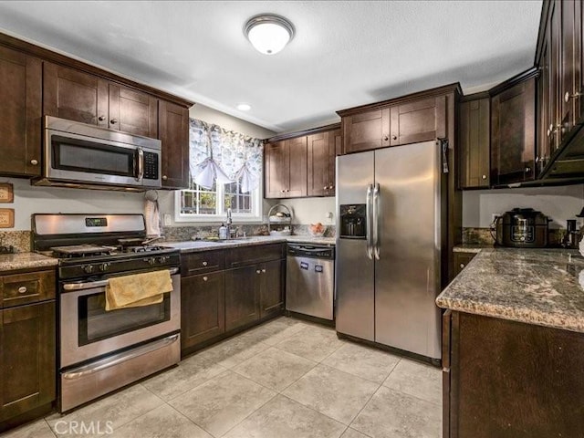 10316 S San Pedro St, Los Angeles, CA 90003 - kitchen featuring stainless steel appliances, dark brown cabinets, light tile patterned flooring, dark stone counters, and recessed lighting