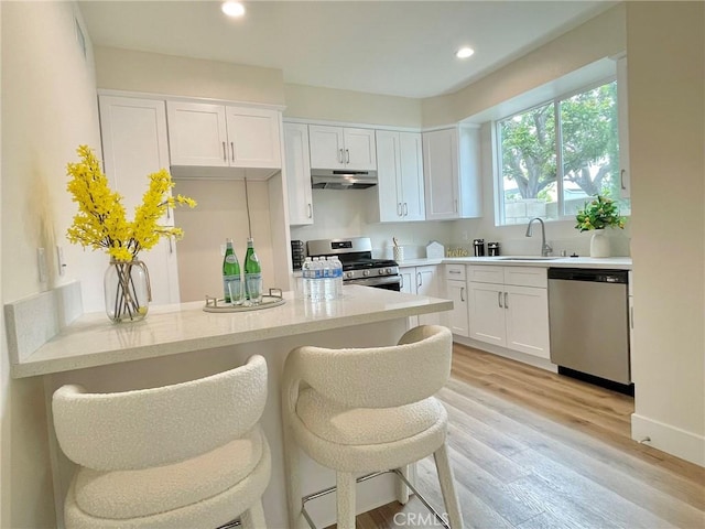 11237 Gladhill Rd Unit 12, Whittier, CA 90604 - kitchen with stainless steel appliances, under cabinet range hood, light countertops, white cabinets, and recessed lighting
