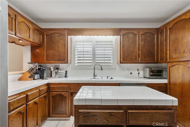 6636 Wooster Ave, Los Angeles, CA 90056 - kitchen with decorative backsplash, tile counters, and brown cabinetry
