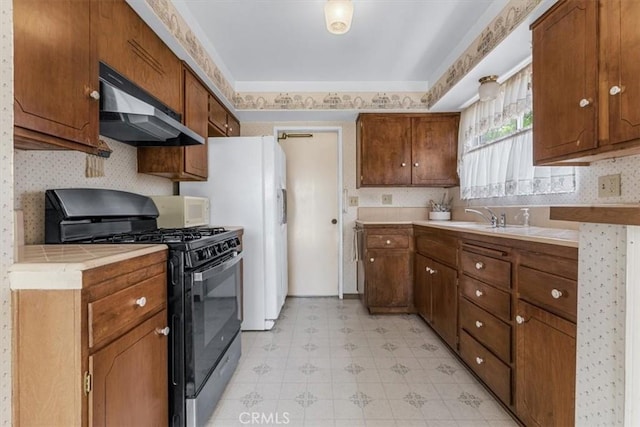 1283 W Newport St, San Luis Obispo, CA 93405 - kitchen with black gas range, under cabinet range hood, light flooring, wallpapered walls, and brown cabinetry
