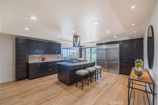 15541 Aqua Verde Dr, Los Angeles, CA 90077 - kitchen featuring stainless steel built in fridge, a kitchen breakfast bar, a center island, light wood-type flooring, and dark cabinetry