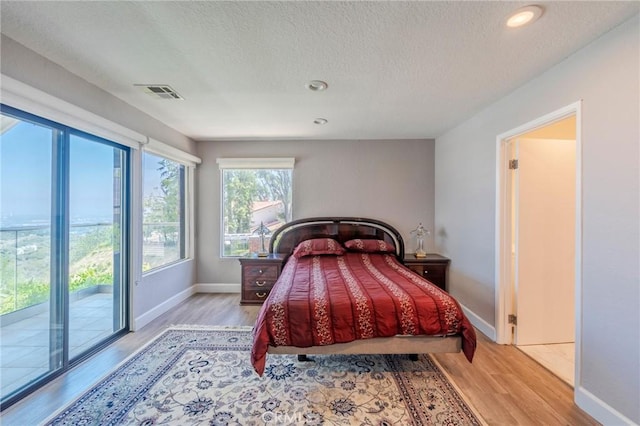 15541 Aqua Verde Dr, Los Angeles, CA 90077 - bedroom featuring access to exterior, light wood-style floors, a textured ceiling, and recessed lighting