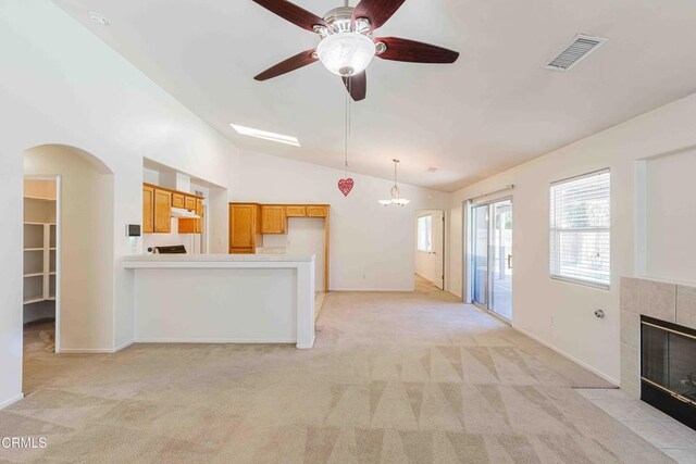 4810 Bluestone Dr, Bakersfield, CA 93311 - kitchen featuring vaulted ceiling, light colored carpet, a tiled fireplace, a ceiling fan, and arched walkways