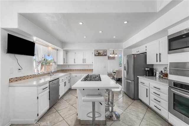 44559 Aspen St, Lancaster, CA 93535 - kitchen featuring stainless steel appliances, a kitchen island, white cabinets, light countertops, and a kitchen bar