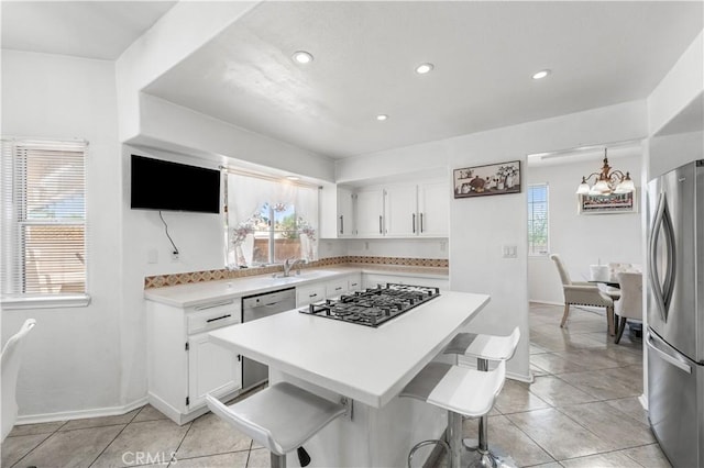 44559 Aspen St, Lancaster, CA 93535 - kitchen with stainless steel appliances, white cabinets, light countertops, a chandelier, and light tile patterned flooring