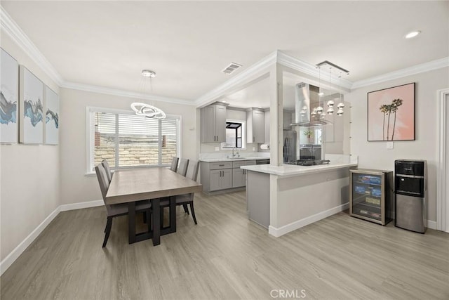 1834 E Stuart Ave, West Covina, CA 91791 - kitchen with gray cabinets, wall chimney range hood, beverage cooler, light wood-type flooring, and crown molding