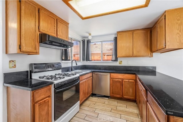 44738 Foxboro Ct, Lancaster, CA 93535 - kitchen featuring range with gas stovetop, under cabinet range hood, stainless steel dishwasher, wood tiled floors, and brown cabinets