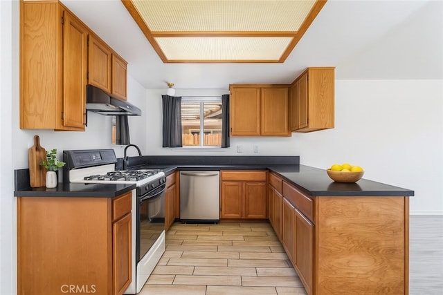 44738 Foxboro Ct, Lancaster, CA 93535 - kitchen featuring stainless steel dishwasher, range with gas stovetop, under cabinet range hood, wood finish floors, and dark countertops