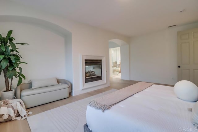 2850 Palmetto Point Ct, Chula Vista, CA 91915 - bedroom with arched walkways, wood finished floors, and a glass covered fireplace
