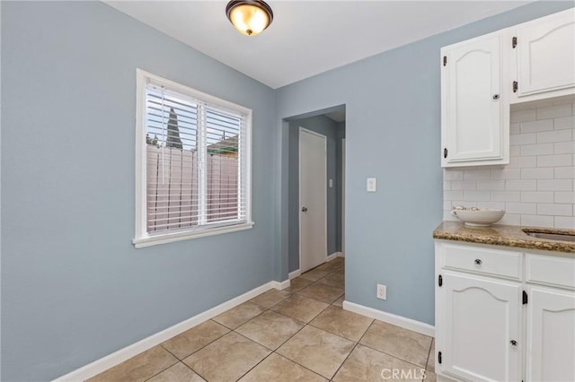 1048 S Record Ave, East Los Angeles, CA 90023 - kitchen featuring white cabinetry, light tile patterned floors, light stone countertops, and decorative backsplash