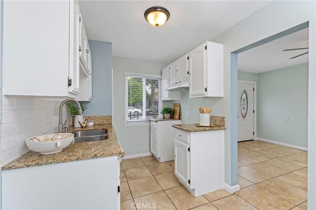 1048 S Record Ave, East Los Angeles, CA 90023 - kitchen with light tile patterned floors, under cabinet range hood, white cabinets, and backsplash