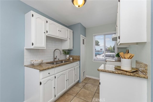 1048 S Record Ave, East Los Angeles, CA 90023 - kitchen with white cabinets, tasteful backsplash, light tile patterned flooring, and stone countertops