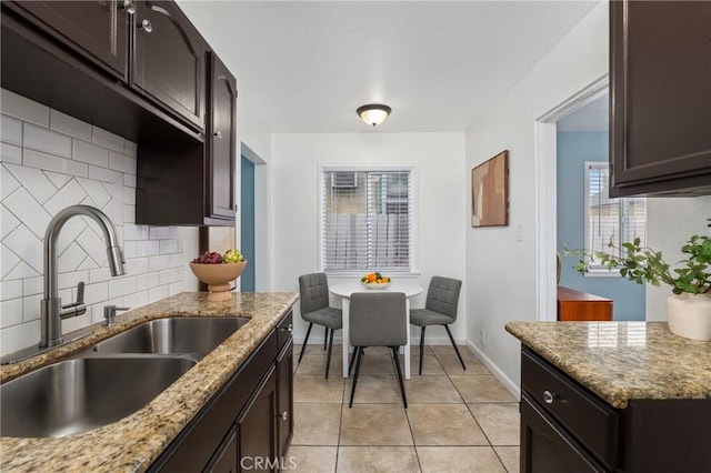 1048 S Record Ave, East Los Angeles, CA 90023 - kitchen with decorative backsplash, dark brown cabinets, light tile patterned flooring, and light stone countertops