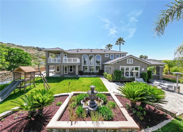 36472 County Line Rd, Yucaipa, CA 92399 - back of house with a yard, stucco siding, a balcony, a patio area, and a playground