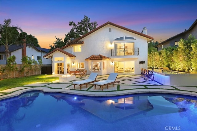 11900 Laughton Way, Porter Ranch, CA 91326 - back of property at dusk featuring a balcony, a patio area, stucco siding, and a tiled roof