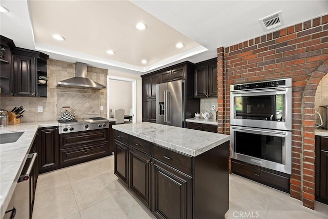 11900 Laughton Way, Porter Ranch, CA 91326 - kitchen featuring wall chimney range hood, stainless steel appliances, open shelves, a tray ceiling, and backsplash