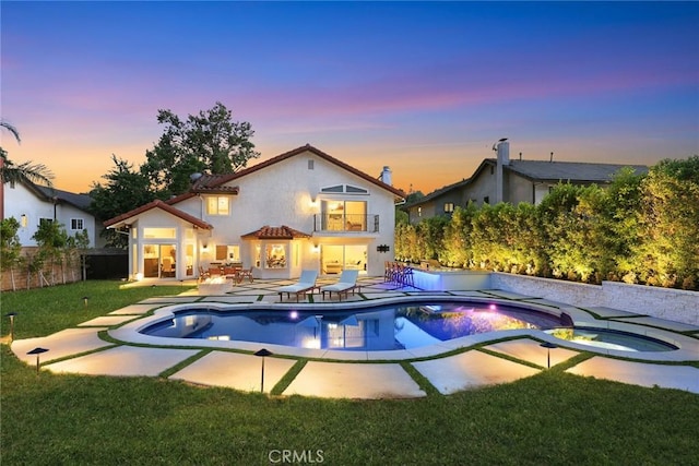 11900 Laughton Way, Porter Ranch, CA 91326 - back of house at dusk featuring an in-ground hot tub, a balcony, stucco siding, and a patio area