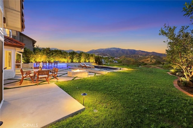11900 Laughton Way, Porter Ranch, CA 91326 - yard at dusk featuring a yard, a patio area, a mountain view, and an outdoor fire pit