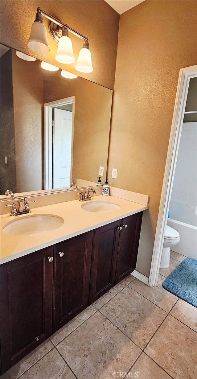 15048 Westin Ln, La Mirada, CA 90638 - bathroom with double vanity, tile patterned flooring, a bathtub, and a textured wall