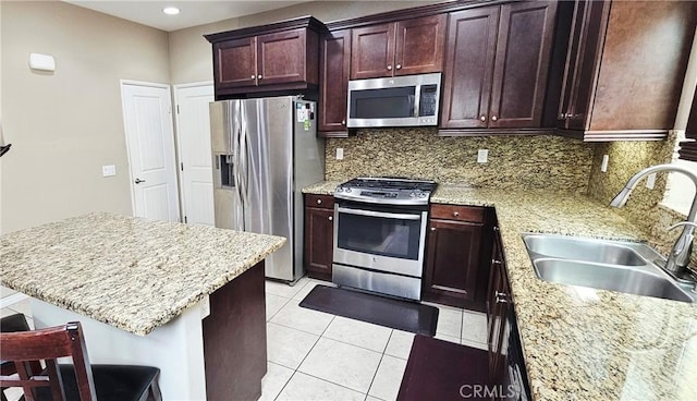 15048 Westin Ln, La Mirada, CA 90638 - kitchen featuring stainless steel appliances, decorative backsplash, light tile patterned floors, light stone countertops, and a breakfast bar