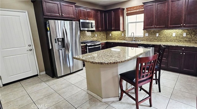 15048 Westin Ln, La Mirada, CA 90638 - kitchen featuring appliances with stainless steel finishes, backsplash, light tile patterned floors, a center island, and light stone counters