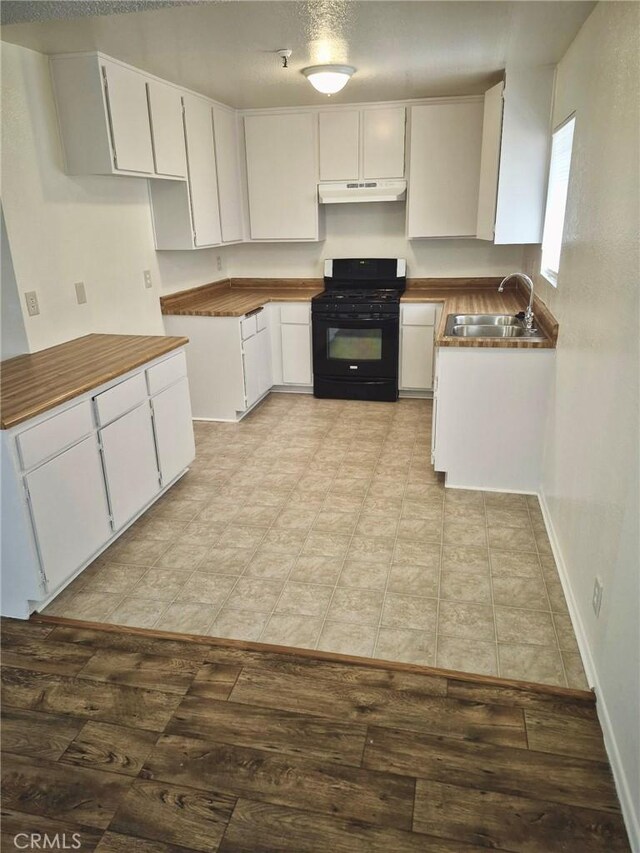 13325 Kornblum Ave, Hawthorne, CA 90250 - kitchen featuring black range with gas stovetop, under cabinet range hood, light wood-style flooring, and white cabinets