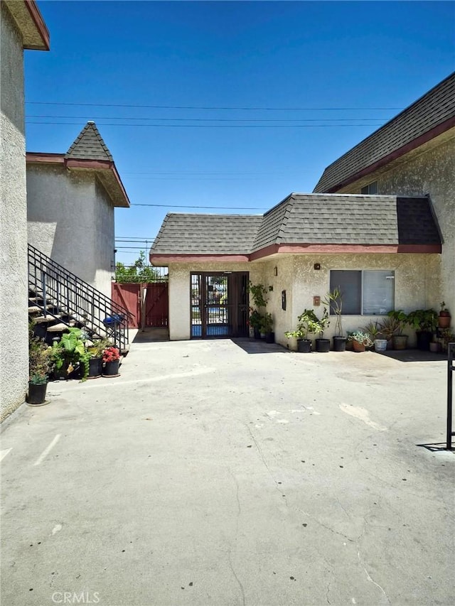 13325 Kornblum Ave, Hawthorne, CA 90250 - exterior space with a shingled roof, stucco siding, mansard roof, and a gate