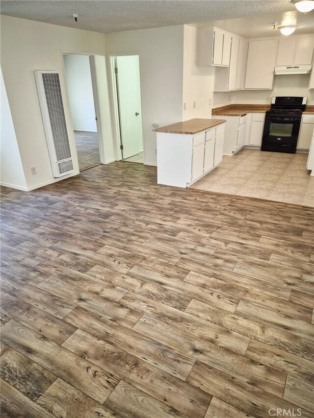 13325 Kornblum Ave, Hawthorne, CA 90250 - kitchen with black range with gas stovetop, a heating unit, wood finished floors, under cabinet range hood, and a textured ceiling