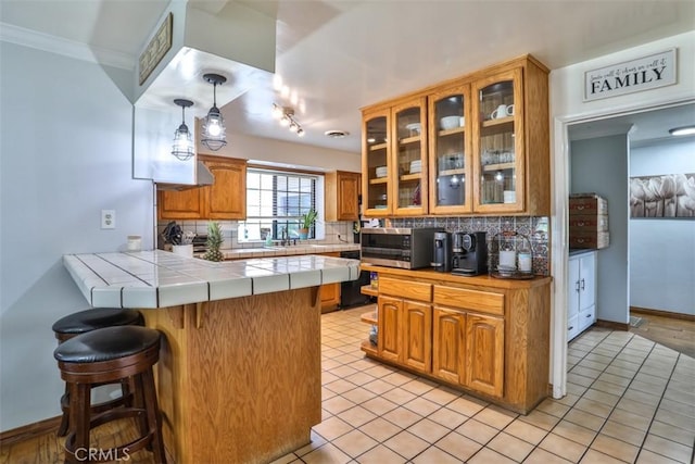 1853 E Renshaw St, Covina, CA 91724 - kitchen with a peninsula, stainless steel microwave, backsplash, a kitchen bar, and ornamental molding