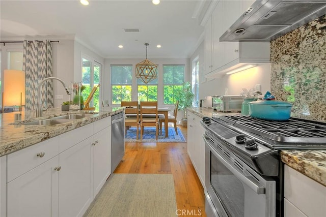 25 Sedgewick, Irvine, CA 92620 - kitchen featuring stainless steel appliances, wall chimney exhaust hood, light wood-type flooring, white cabinets, and backsplash