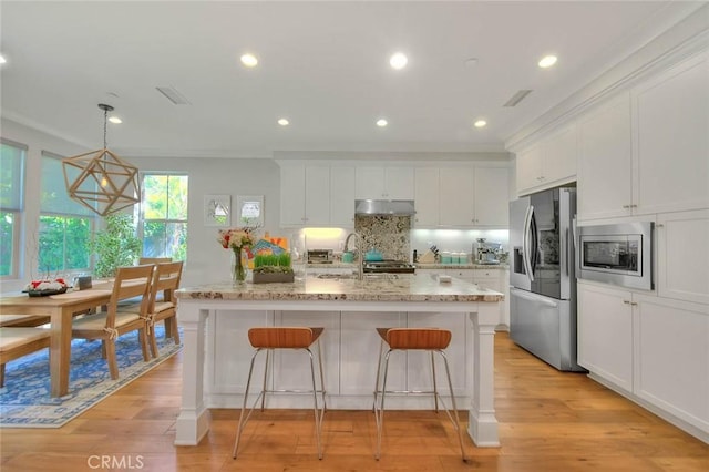 25 Sedgewick, Irvine, CA 92620 - kitchen with stainless steel appliances, under cabinet range hood, white cabinets, a kitchen breakfast bar, and recessed lighting