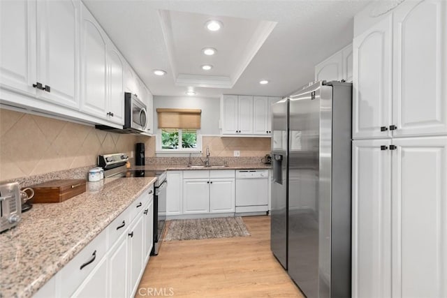 856 Ronda Mendoza Unit P, Laguna Woods, CA 92637 - kitchen with appliances with stainless steel finishes, light wood finished floors, a tray ceiling, white cabinetry, and light stone counters