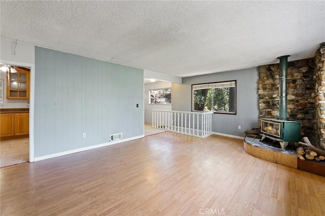 25286 N Rd, Twin Peaks, CA 92391 - unfurnished living room featuring a wood stove, light wood-style flooring, and a textured ceiling