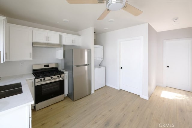 728 Euclid St, Santa Monica, CA 90402 - kitchen with stainless steel appliances, stacked washer / dryer, under cabinet range hood, light countertops, and white cabinetry