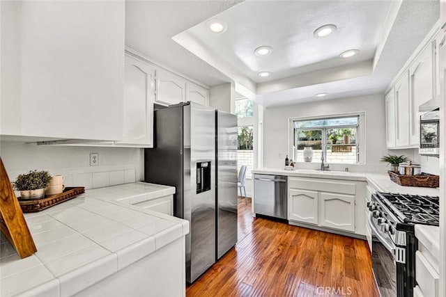 3401 Mountainside Cir, Corona, CA 92882 - kitchen with appliances with stainless steel finishes, tile counters, a raised ceiling, white cabinets, and recessed lighting