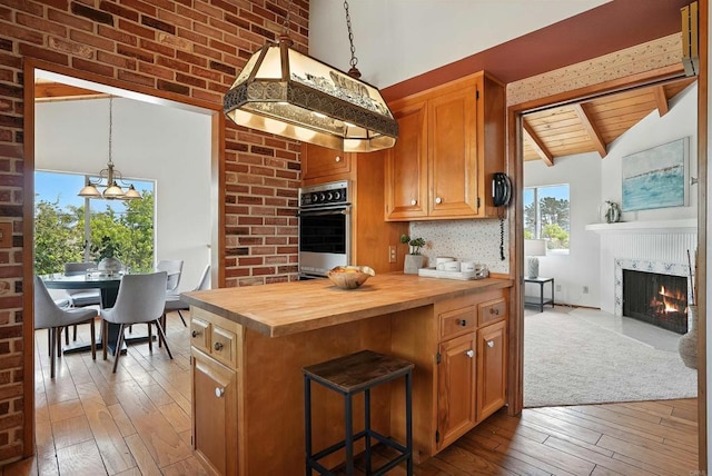 311 Corto, Solana Beach, CA 92075 - kitchen featuring butcher block countertops, stainless steel oven, hardwood / wood-style floors, a fireplace with flush hearth, and pendant lighting