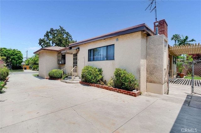 5856 E Scrivener St, Long Beach, CA 90808 - view of front of house with stucco siding, a patio, a chimney, a pergola, and a gate