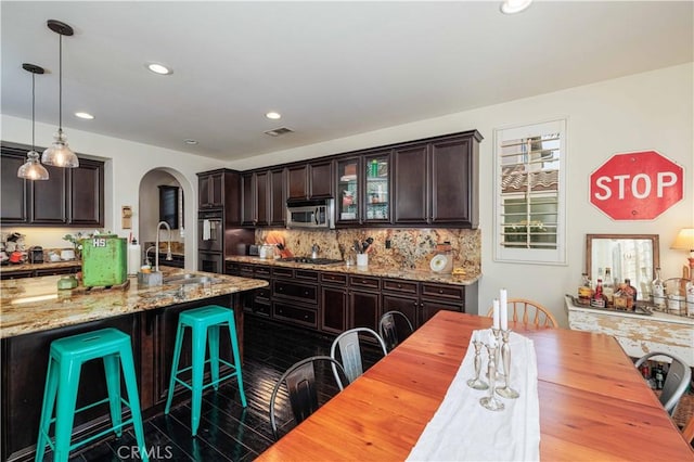 1759 Crebs Way, Upland, CA 91784 - kitchen featuring stainless steel appliances, arched walkways, dark brown cabinetry, tasteful backsplash, and a breakfast bar area