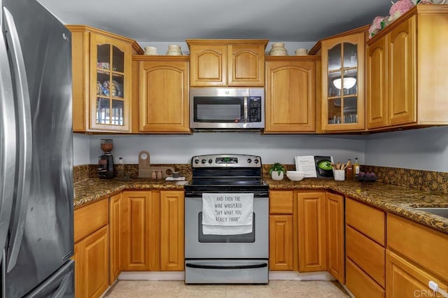 7215 San Pasqual St, Lemon Grove, CA 91945 - kitchen featuring appliances with stainless steel finishes, dark stone counters, glass insert cabinets, and brown cabinets