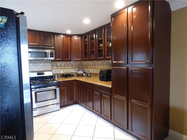 630 W Santa Cruz St, San Pedro, CA 90731 - kitchen featuring appliances with stainless steel finishes, decorative backsplash, light tile patterned flooring, glass insert cabinets, and light stone counters