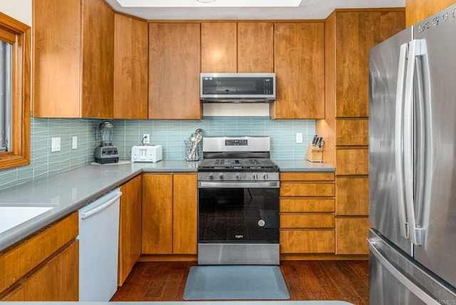 157 Beechtree Dr, Encinitas, CA 92024 - kitchen with appliances with stainless steel finishes, dark wood-style flooring, tasteful backsplash, brown cabinets, and light countertops