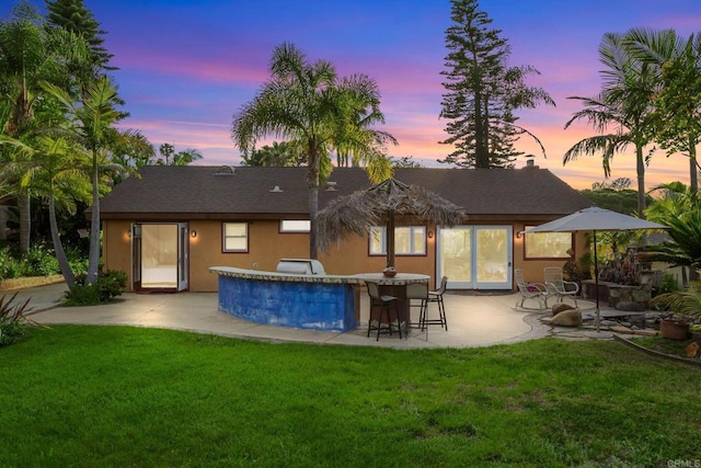 157 Beechtree Dr, Encinitas, CA 92024 - back of house at dusk featuring a patio, a lawn, a shingled roof, and stucco siding
