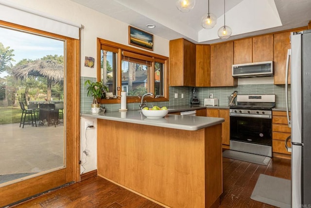 157 Beechtree Dr, Encinitas, CA 92024 - kitchen with stainless steel appliances, a peninsula, brown cabinets, dark wood-type flooring, and decorative backsplash